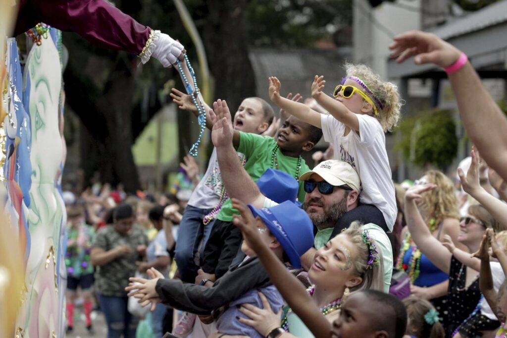 Children catching beads from a Mardi Gras float