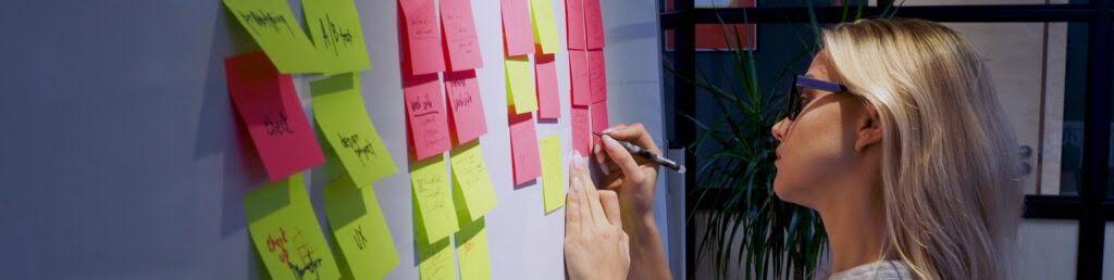 Girl writing on sticky note on kanban board