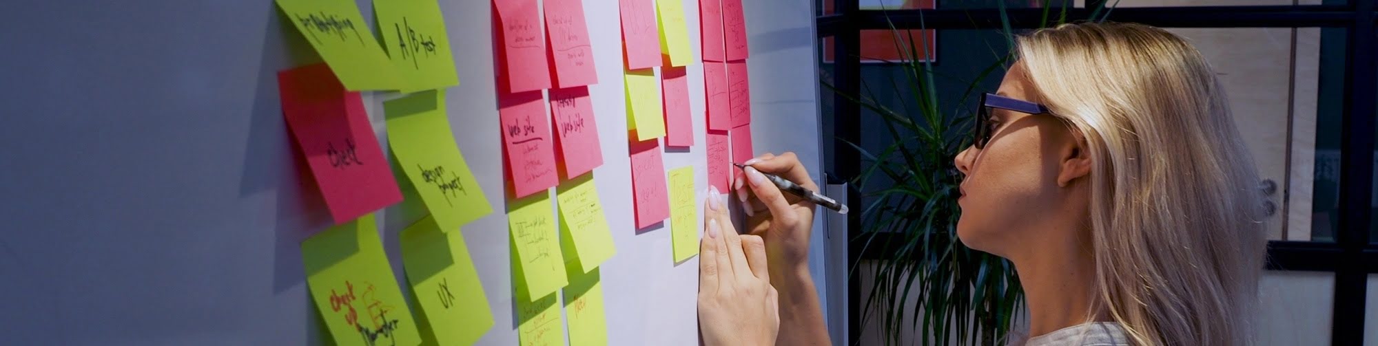 Girl writing on sticky note on kanban board